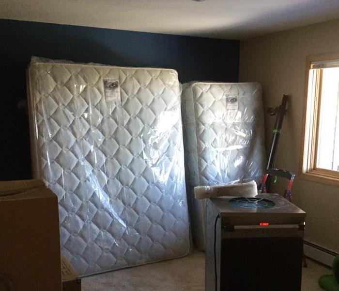 mattresses wrapped in plastic leaning up against a wall in a bed room